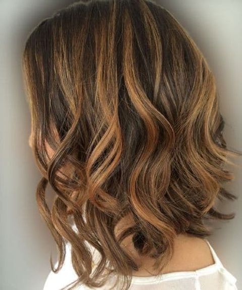 Wavy mid-length hairstyle with caramel highlight